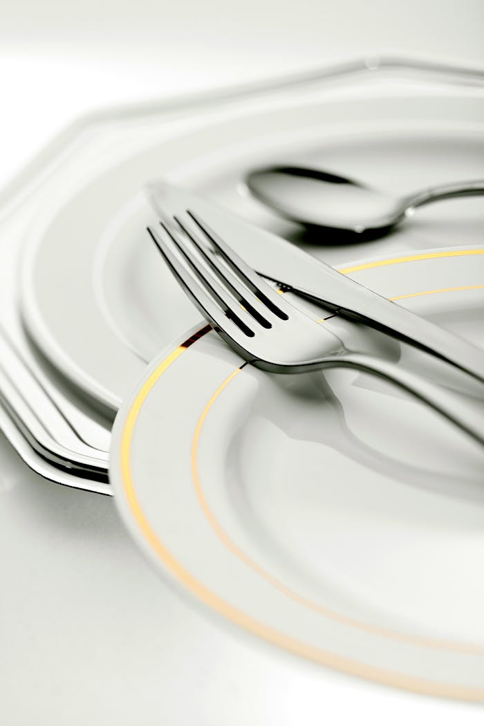 about-02 Close-up of elegant plates and silver cutlery, ideal for dining settings.
