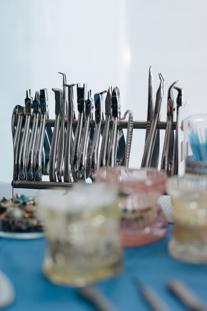 gallery-5 A set of stainless steel dental tools displayed on a blue surface in a clinic setting.
